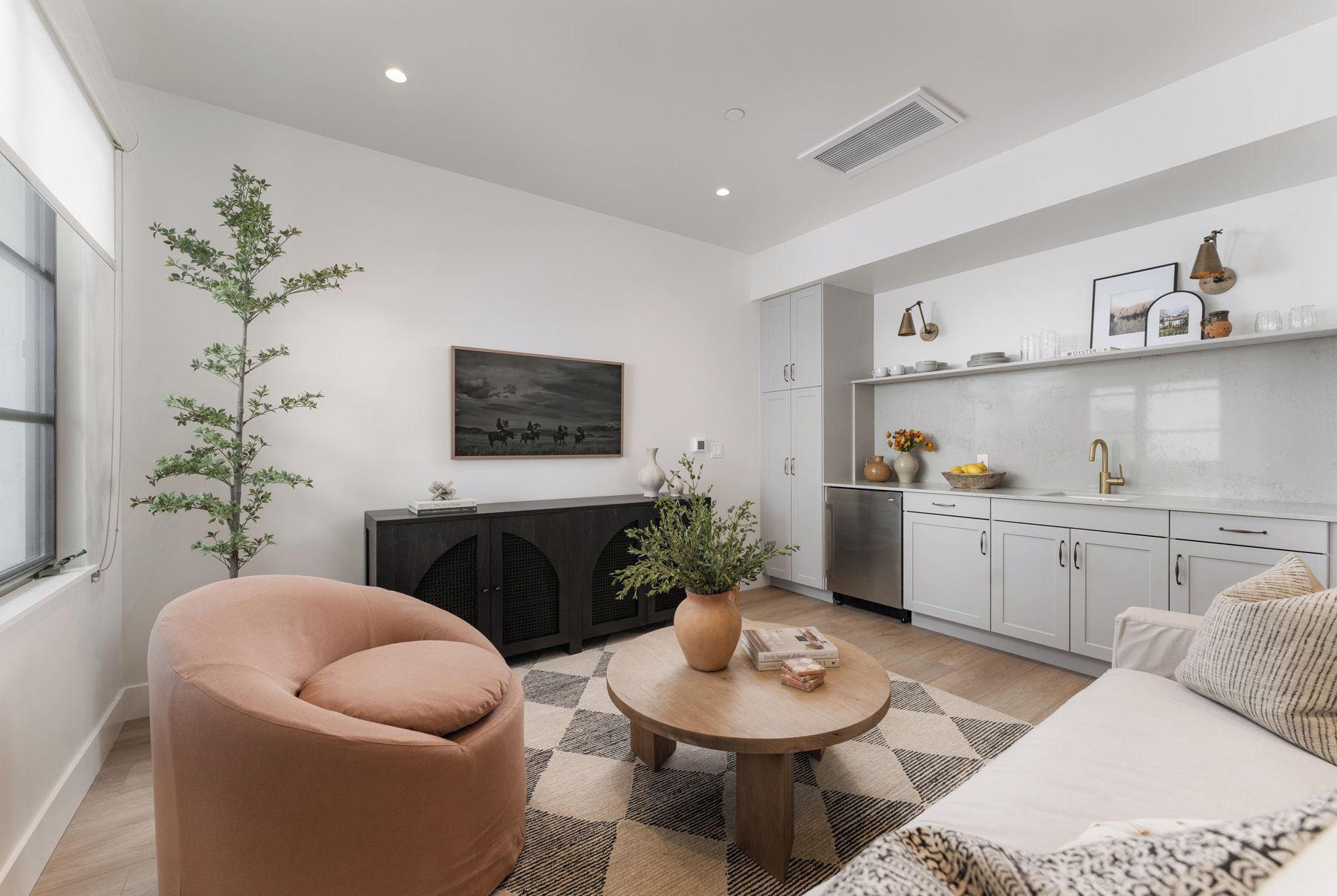 Een moderne woonkamer met een bank, een rond bijzettafeltje en een potplant.