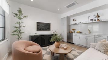 Een moderne woonkamer met een bank, een rond bijzettafeltje en een potplant.
