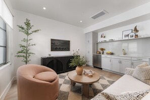A modern living room with a sofa, a round coffee table, and a potted plant.