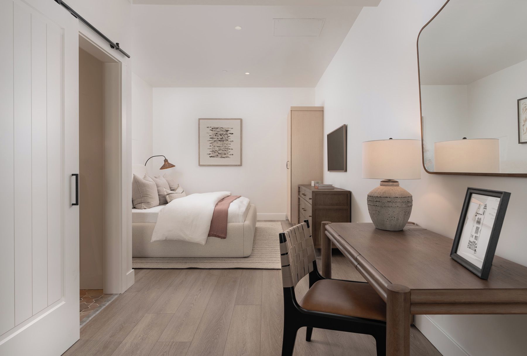 A modern bedroom with a bed, bedside table, lamp, and a framed picture.