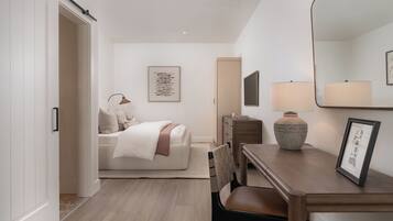 A modern bedroom with a bed, bedside table, lamp, and a framed picture.