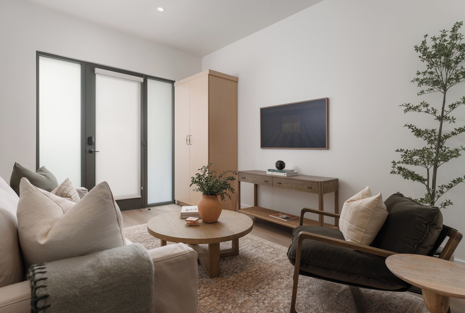 Una sala de estar moderna con sofá, mesa de centro, escritorio y planta en maceta.