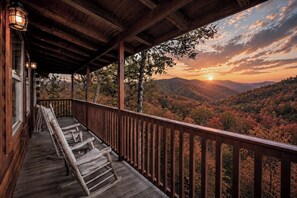 Eine Holzterrasse mit Geländer, die einen bewaldeten Talblick im Abendlicht bietet.