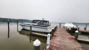 A boat docked at a wooden pier with a calm lake in the background.