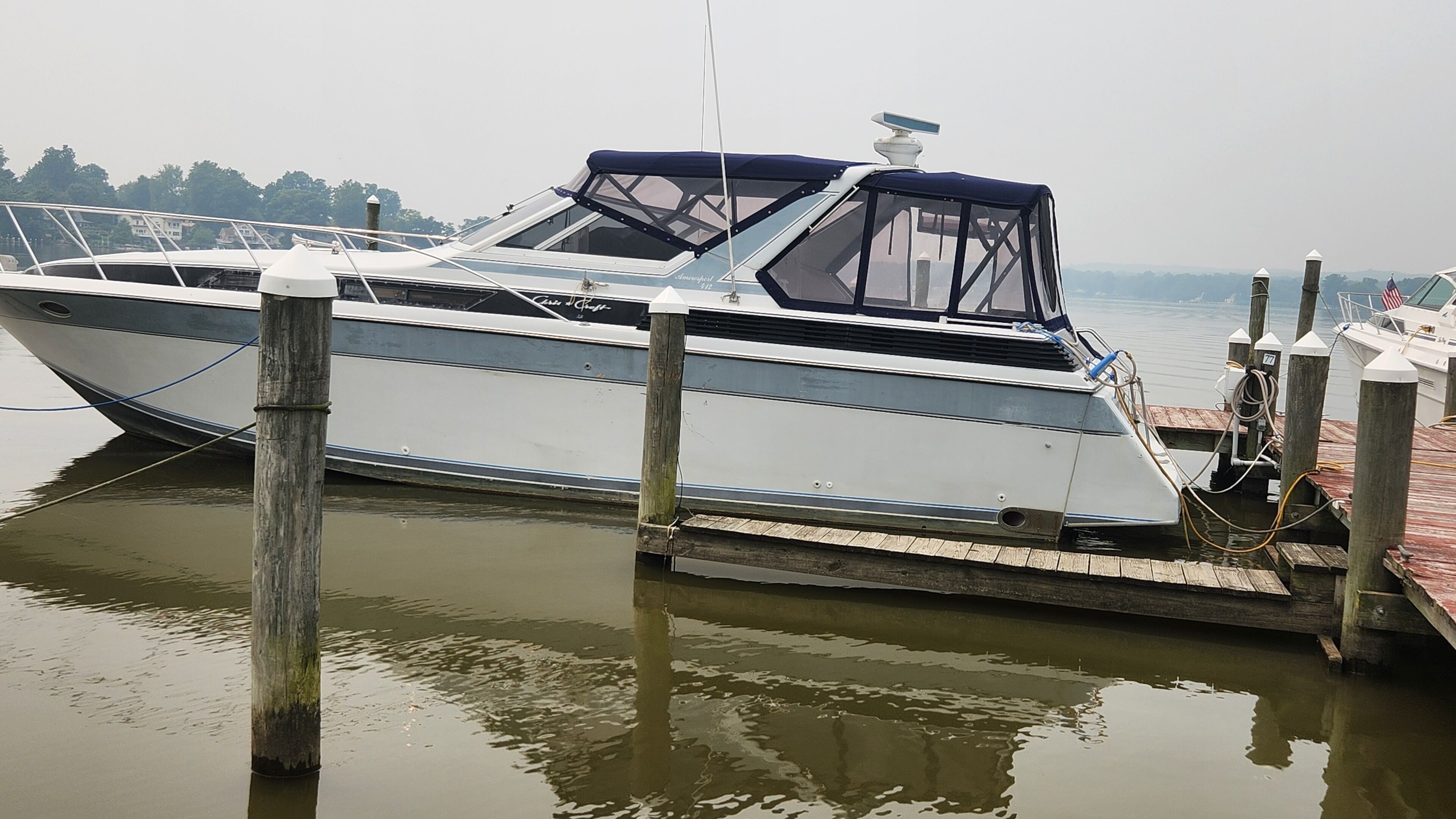 A boat docked at a wooden pier with a clear view of the water and a distant shoreline.