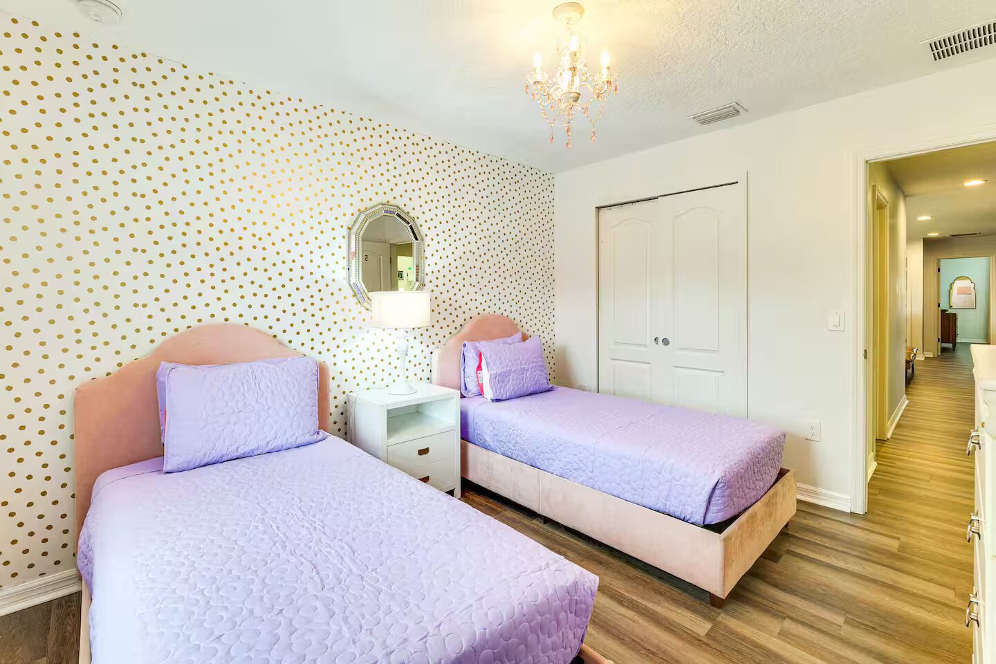 Een slaapkamer met twee bedden, een nachtkastje, een spiegel en een kroonluchter.
