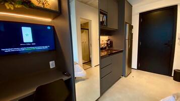 Una cocina moderna con un refrigerador empotrado, un microondas y una cafetera. Hay una zona de comedor con una mesa y sillas.