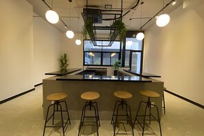 Eine moderne Bar mit einer zentralen Theke, vier Barhocker und h ängenden Pflanzen.