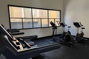 A gym with exercise equipment including treadmills and stationary bikes, large windows with a view of buildings. - SHB Studio incrível a 3 min da Paulista (São Paulo)