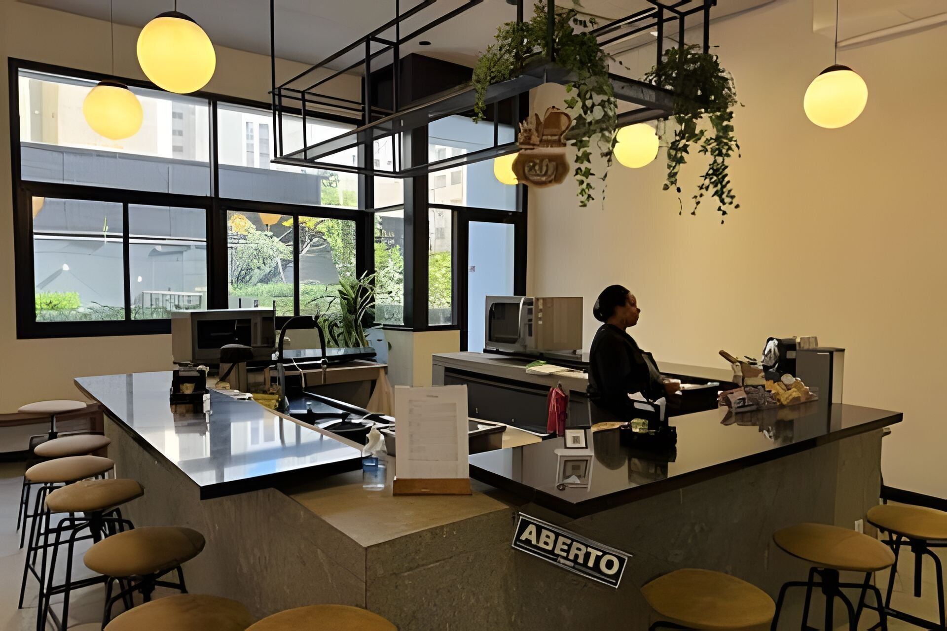 Un área de bar moderna con una barra central, taburetes y un letrero que dice "ABERTO".