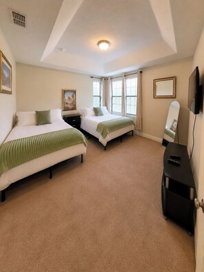 A hotel room with two beds, a flat-screen TV, a large window, and a ceiling vent. - Modern Champions Gate Retreat - 2 Primary Suites - 5 Beds - Sleeps 10 (Davenport)