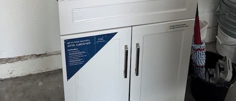 Un meuble compact tout-en-un pour évier de buanderie, doté d’un évier en acier inoxydable, d’un robinet et d’un distributeur de savon.