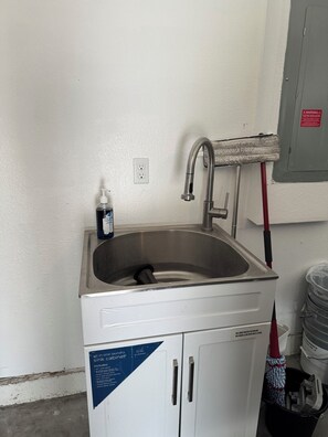 Ein kompakter, alles-in-einem Waschbecken-Schrank mit Edelstahlbecken, Wasserhahn und Seifenspender.