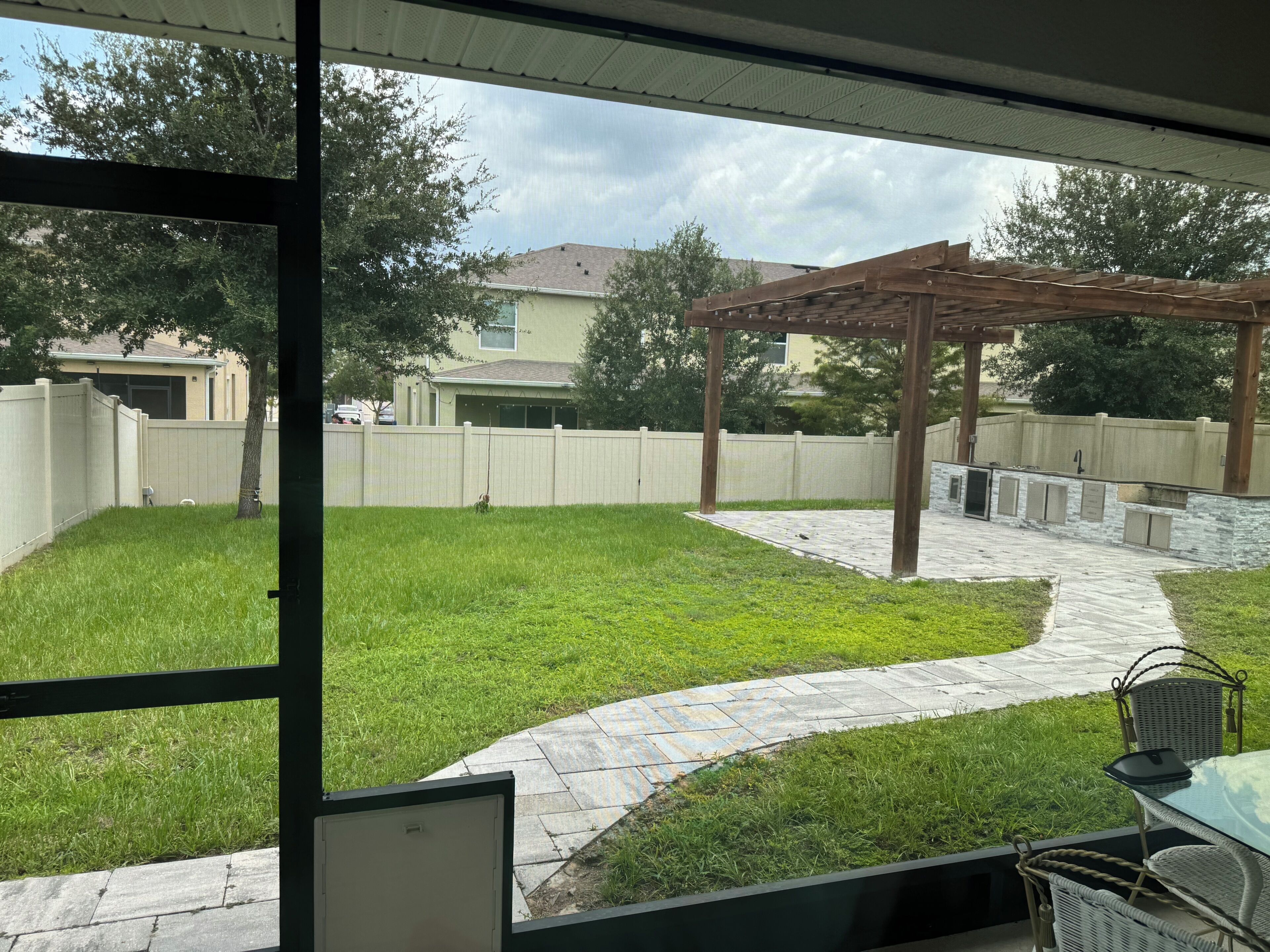 Un patio trasero con un pérgola, un patio de piedra y un césped.