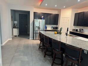A modern kitchen with a granite countertop, stainless steel appliances, and dark wooden cabinets. - House for rent, 12 minutes from Orlando Airport and 25 minutes from the parks. (Orlando)