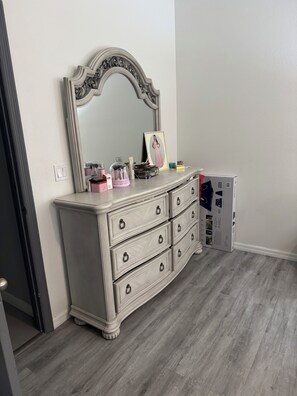 A white dresser with a mirror, drawers, and a small shelf with various items. - House for rent, 12 minutes from Orlando Airport and 25 minutes from the parks. (Orlando)