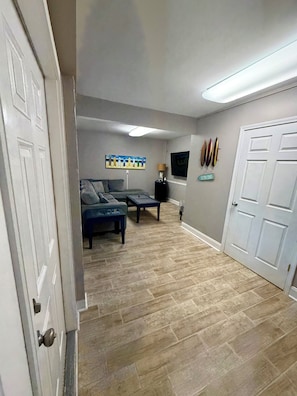 A room with a grey sofa, a coffee table, a TV, and a door with a sign. - Where Isle Be•Relax & Unwind• 4 bed• 4 bath• Sleeps 8 (Emerald Isle)