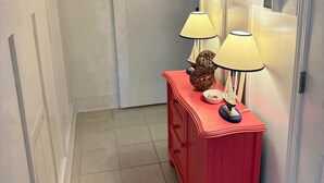 Une salle de bain avec une baignoire blanche, un meuble-lavabo rouge avec deux lampes et un porte-serviettes au-dessus de la baignoire.