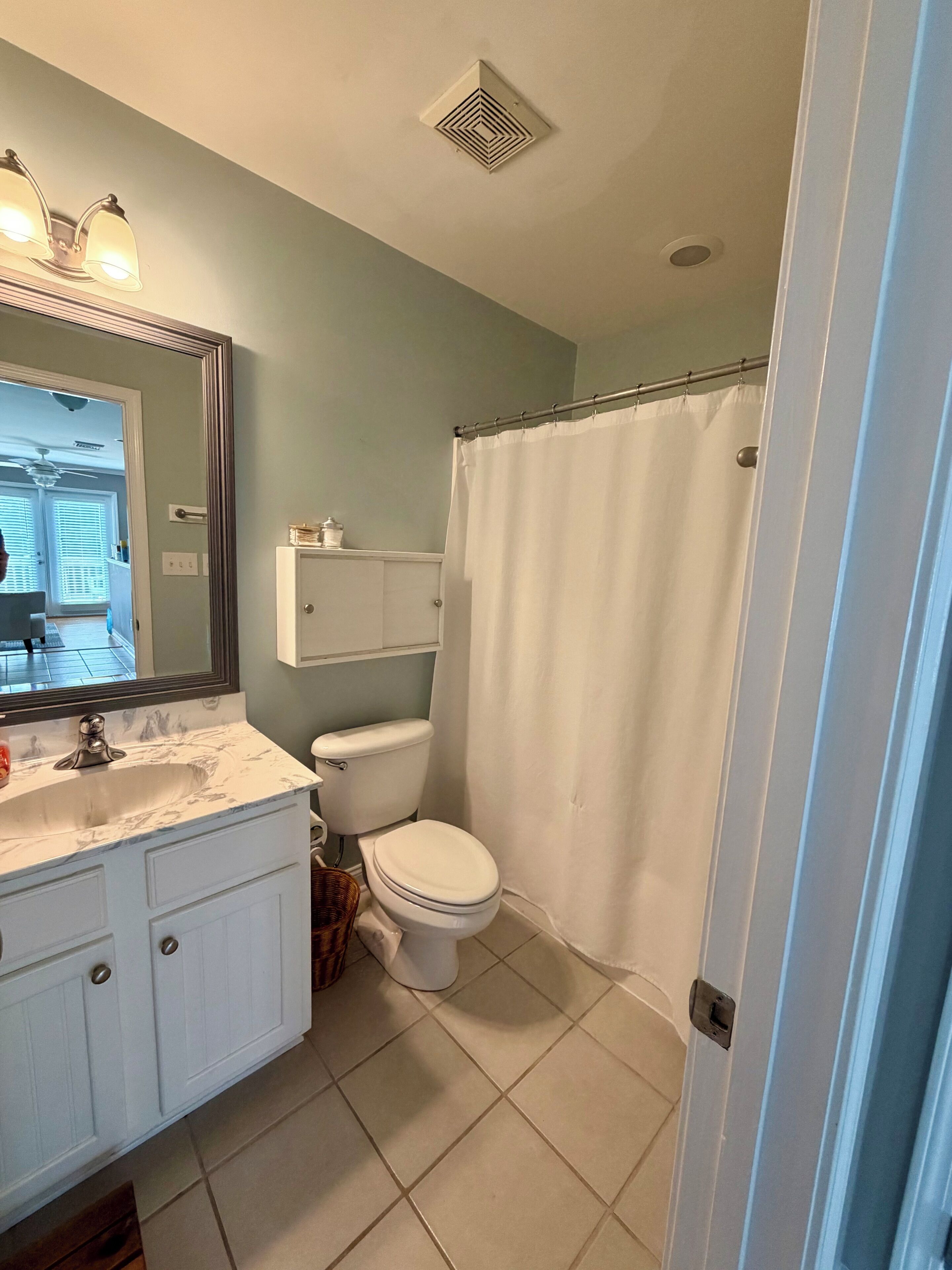 A bathroom with a toilet, sink, mirror, and shower curtain.