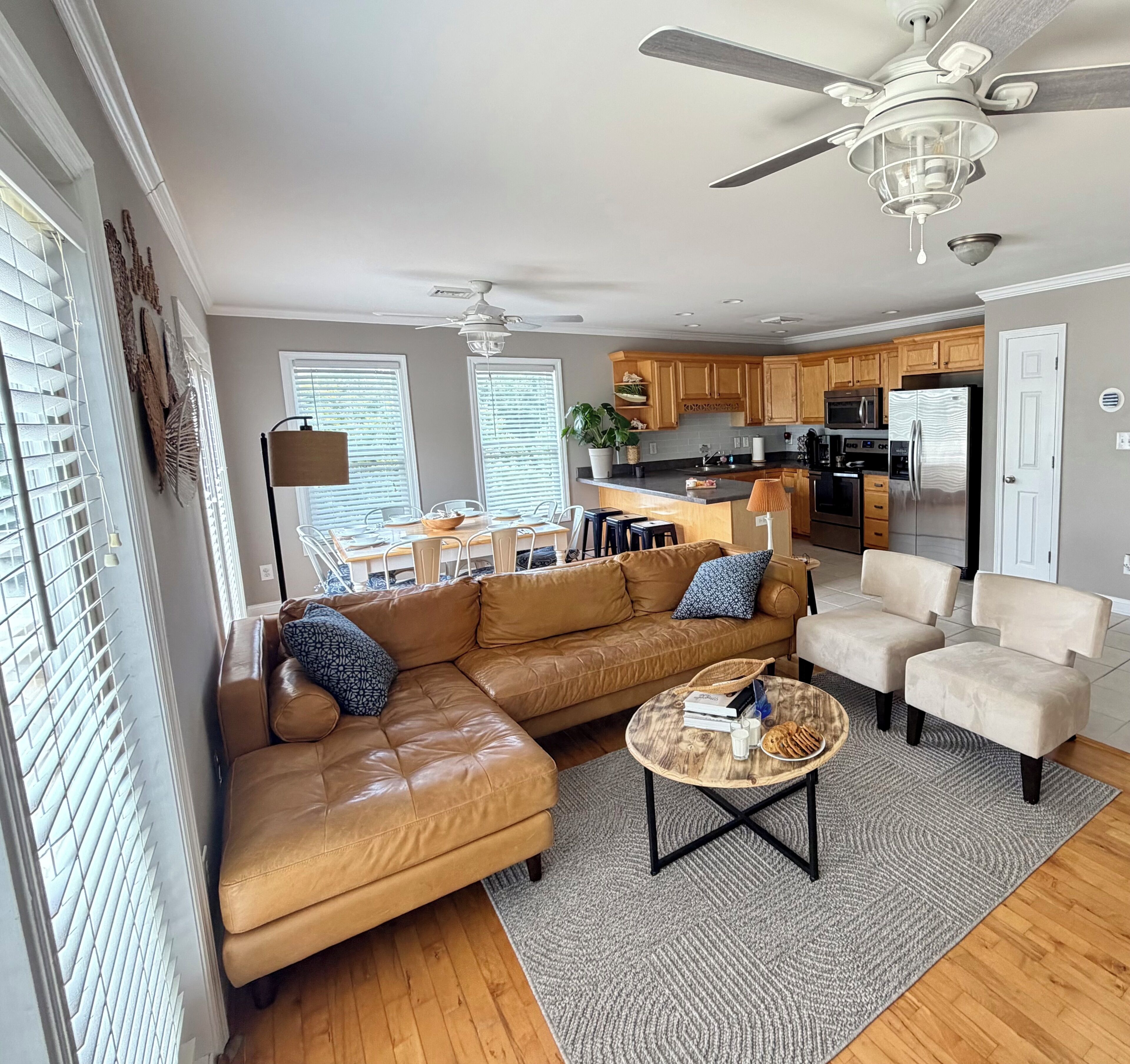 A modern living room with a leather sofa, a coffee table, and a dining area with a kitchen in the background.