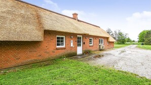 Una casa de ladrillo con techo de paja, camino de grava y zona ajardinada.