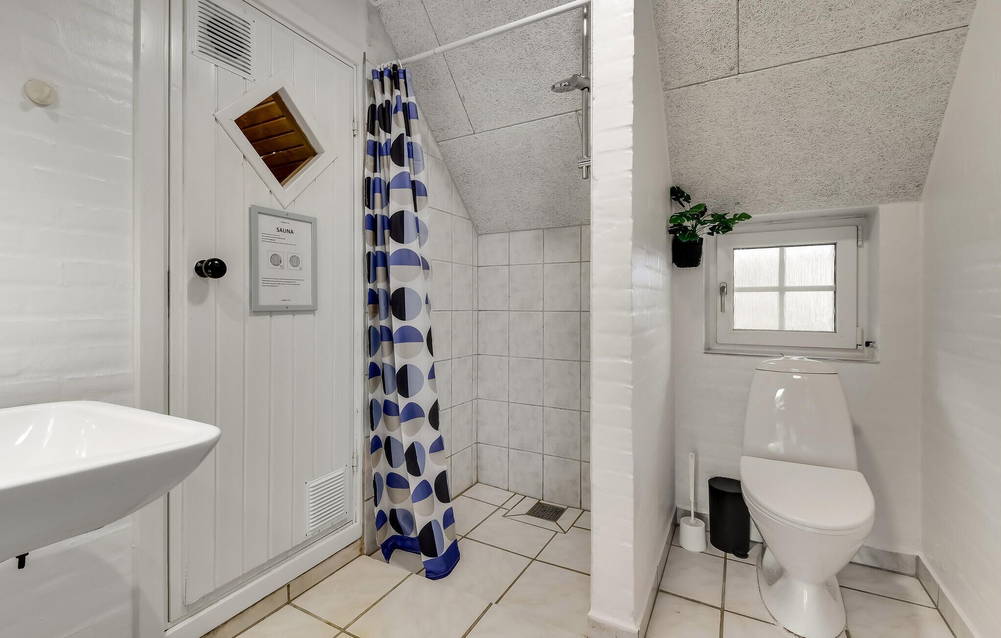A bathroom with a shower, a toilet, a sink, and a window.