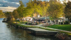 A lakeside property with a dock, outdoor seating, and a building with a green roof. - The Coosa Nova at River Rocks Landing (Gadsden)