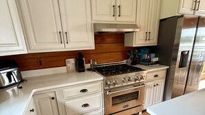 Eine Küche mit weißen Schränken, einem Edelstahlkühlschrank und Holzboden.