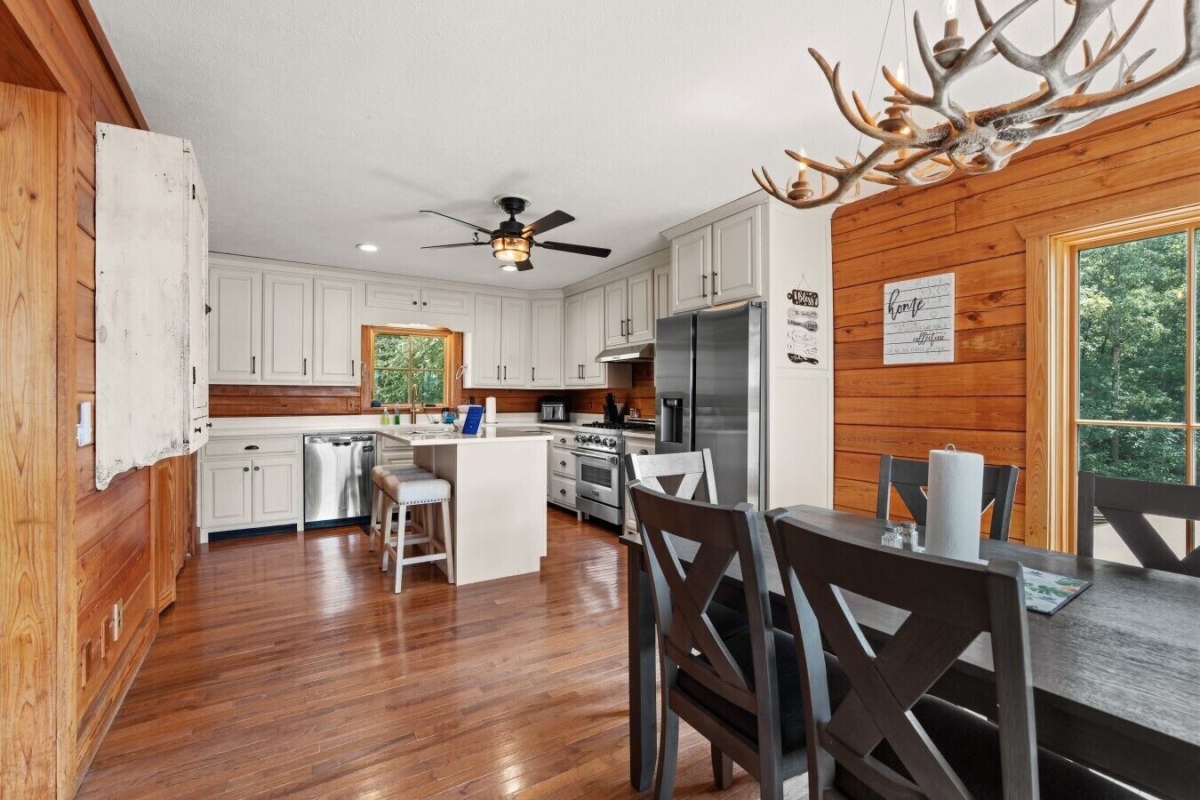 A modern kitchen with white cabinets, a central island, and a dining area with wooden chairs.