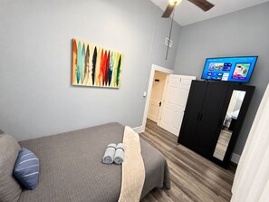 Ein Hotelzimmer mit Bett, Fernseher, Kleiderschrank und einem Bild an der Wand.