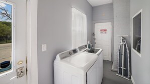 A laundry area with a front-loading washer and dryer, a door with a 'No Entry' sign, and a window with a view of trees. - Downtown Mansion 10 bedrooms/7.5 baths, 34+ people, 11car gated parking, Jacuzzi (San Antonio)