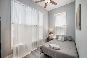 A bedroom with a bed, a nightstand, a lamp, and sheer curtains. - Downtown Mansion 10 bedrooms/7.5 baths, 34+ people, 11car gated parking, Jacuzzi (San Antonio)