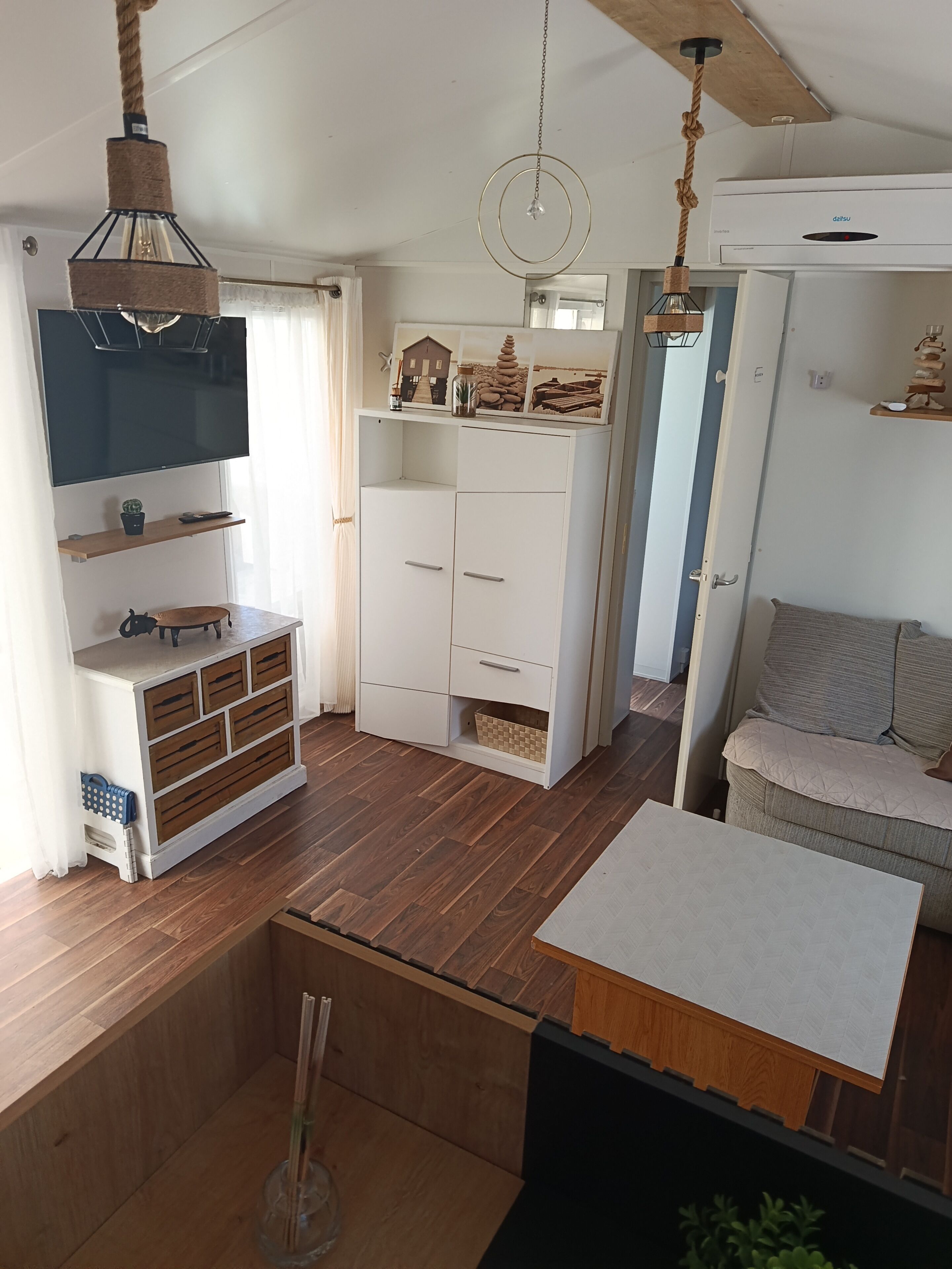 Una sala de estar moderna con una televisión de pantalla plana, piso de madera, un sofá y un comedor.