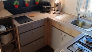 Eine kleine Küche mit Gaskochfeld, Kaffeemaschine und Mikrowelle.
