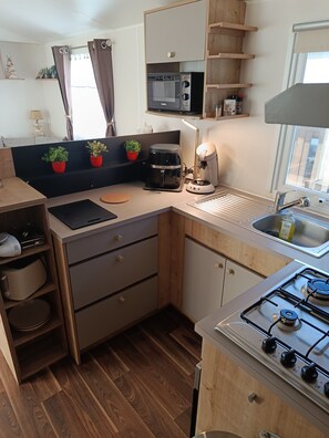 A compact kitchen with a gas stove, a coffee maker, and a microwave. - Mobile home 50 meters from the beach Natural surroundings Family vacations (Agde)
