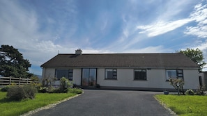 Ein eingeschossiges Haus mit Ziegeldach, Hauseingang und befestigter Auffahrt.