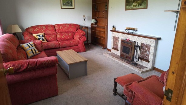 Ein Wohnzimmer mit einem roten Sofa, einem Holztisch und einem Kamin.