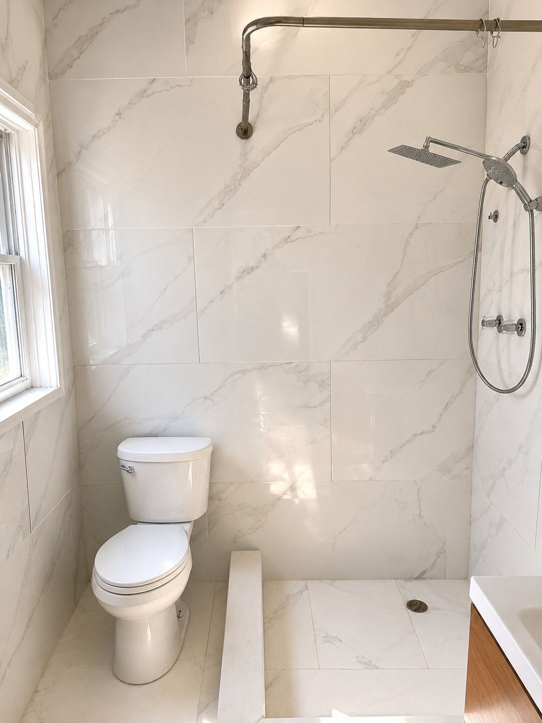 Un baño con inodoro, ducha con cabezal de ducha manual y ventana.