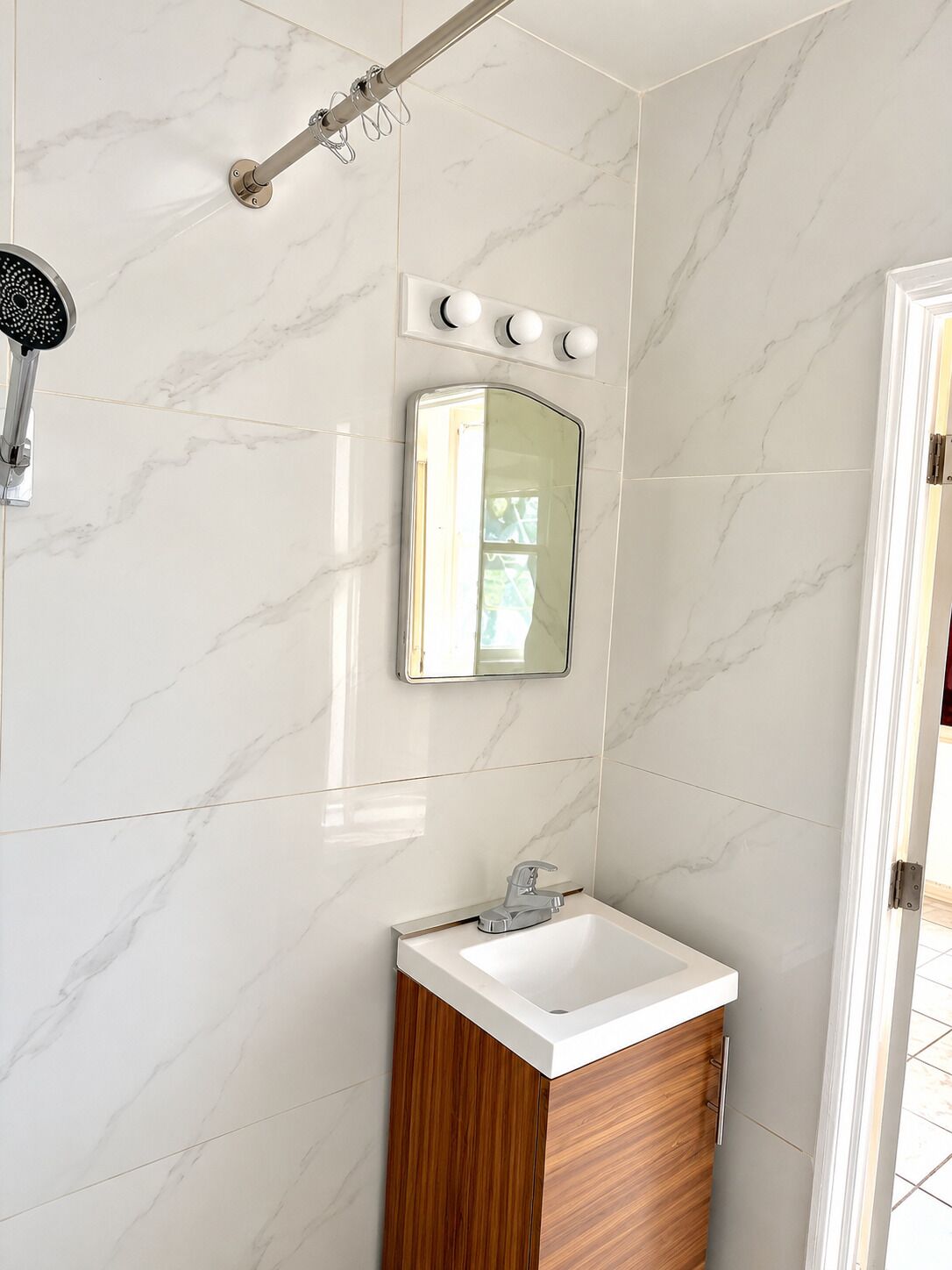 Un baño con ducha, lavamanos y espejo.
