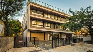 A multi-story building with a ground-level entrance, a balcony on the second floor, and a storefront with signage. - Studio Saint Garden - Sunset - Swimming pool with ocean view - Gastronomy (Florianópolis)