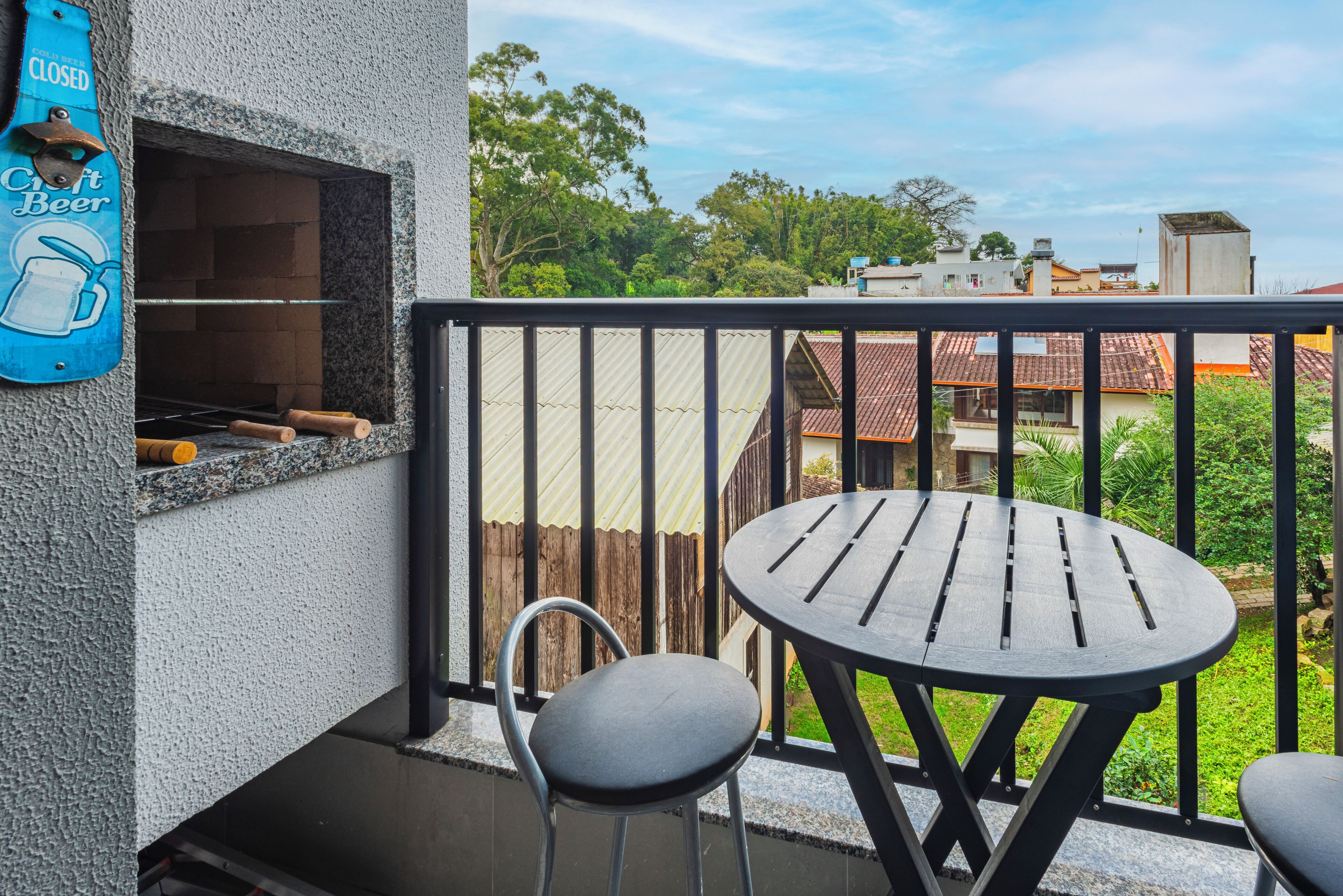 A balcony with a grill, a table, and two chairs.