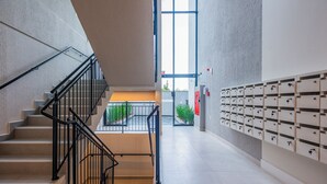 A modern interior with a staircase, a row of mailboxes, and a large window. - Studio Saint Garden - Sunset - Swimming pool with ocean view - Gastronomy (Florianópolis)