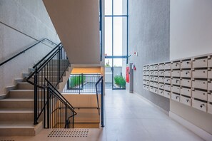 Ein modernes Interieur mit einer Treppe, einer Reihe von Briefkästen und einem großen Fenster.