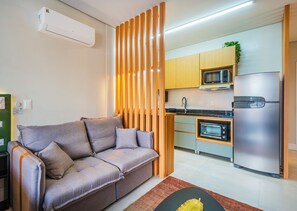 A modern kitchen with a built-in microwave, oven, and refrigerator. - Studio Saint Garden - Sunset - Pool with Ocean View - Dining (Florianópolis)