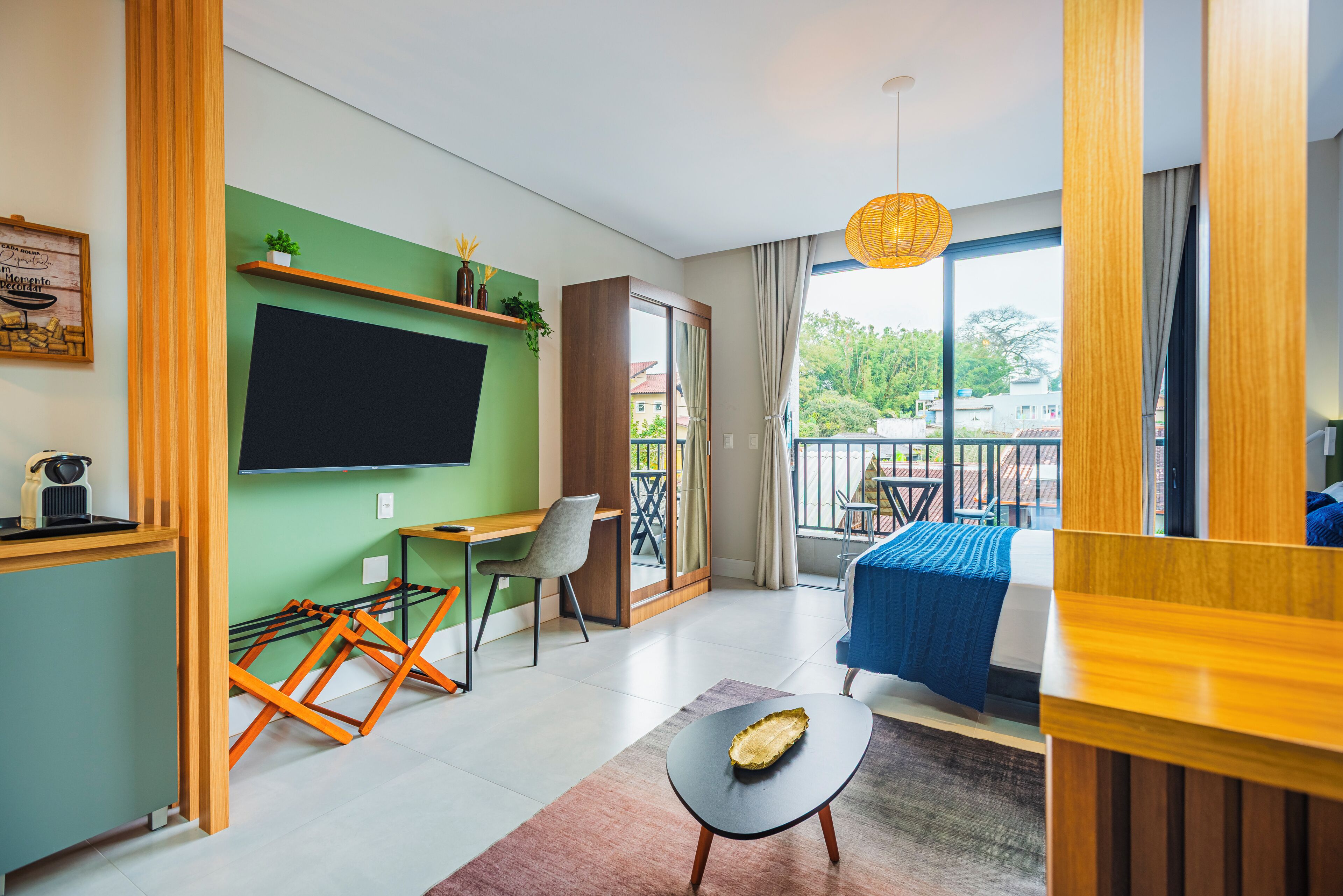 Une chambre d’hôtel moderne dotée d’un grand lit, d’un bureau avec une chaise, d’un balcon avec vue et d’un téléviseur fixé au mur.