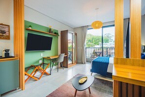 A modern hotel room with a large bed, a desk with a chair, a balcony with a view, and a television mounted on the wall. - Studio Saint Garden - Sunset - Swimming pool with ocean view - Gastronomy (Florianópolis)