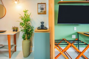 A room with a desk, a large plant, a framed picture, a blackboard, and a folding chair. - Studio Saint Garden - Sunset - Swimming pool with ocean view - Gastronomy (Florianópolis)