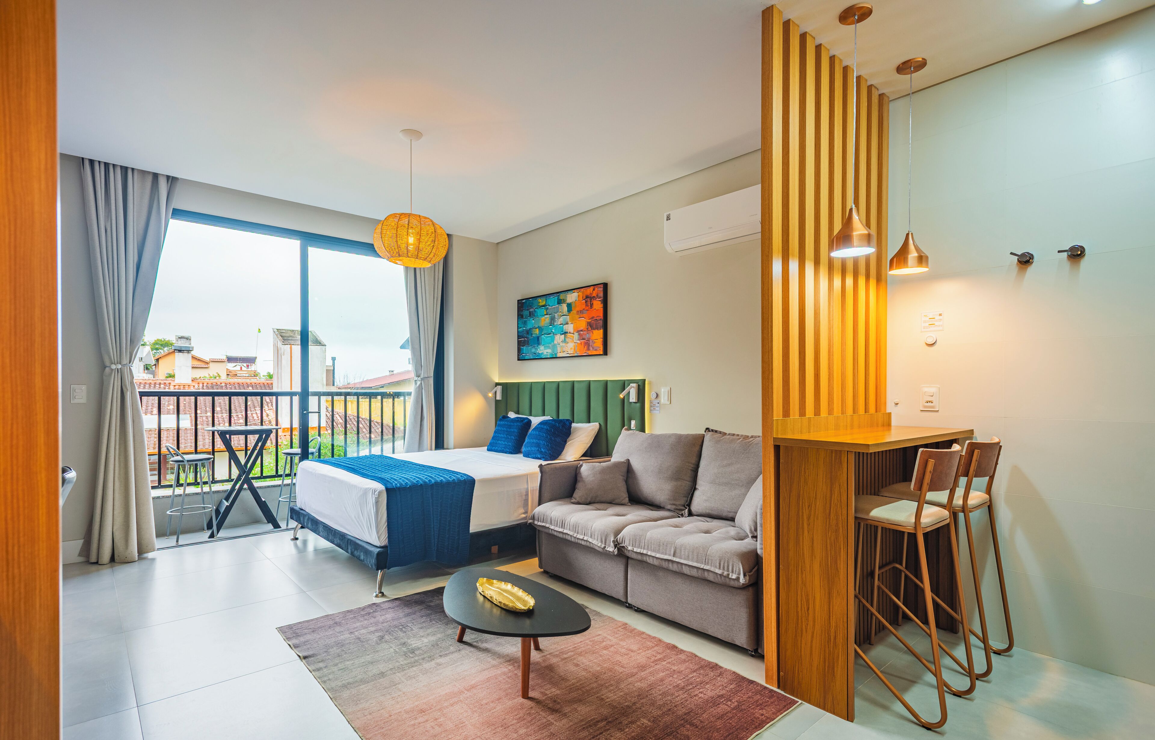Quarto de hotel moderno com varanda, sofá, cama e área de refeições.
