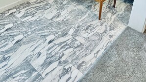 A living room with a grey sofa, patterned cushions, a wooden coffee table, and a marble-patterned floor. - Oceanfront Condo Newly Renovated (Hampton)