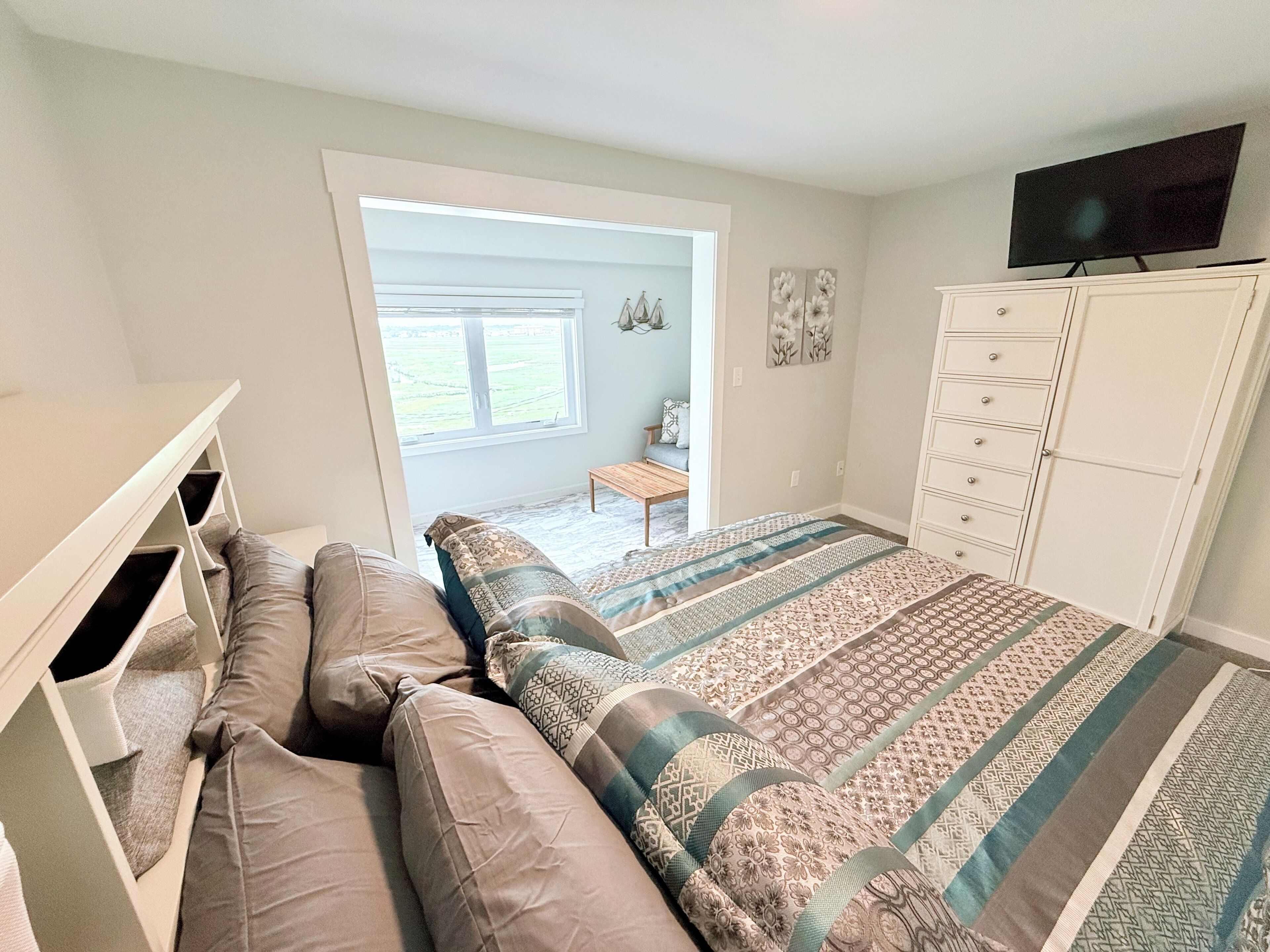 A bedroom with a bed, a dresser, a television, and a window.